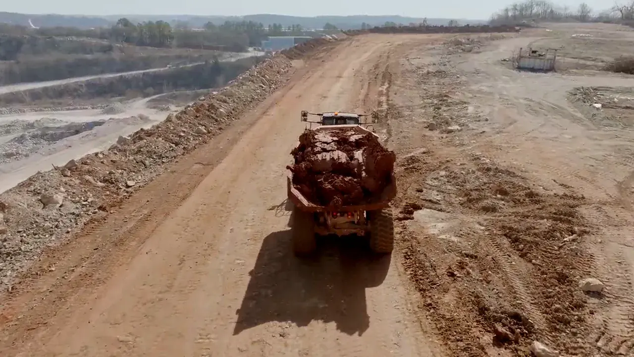Vue du drone : un camion chargé roule sur une piste de chantier minier.